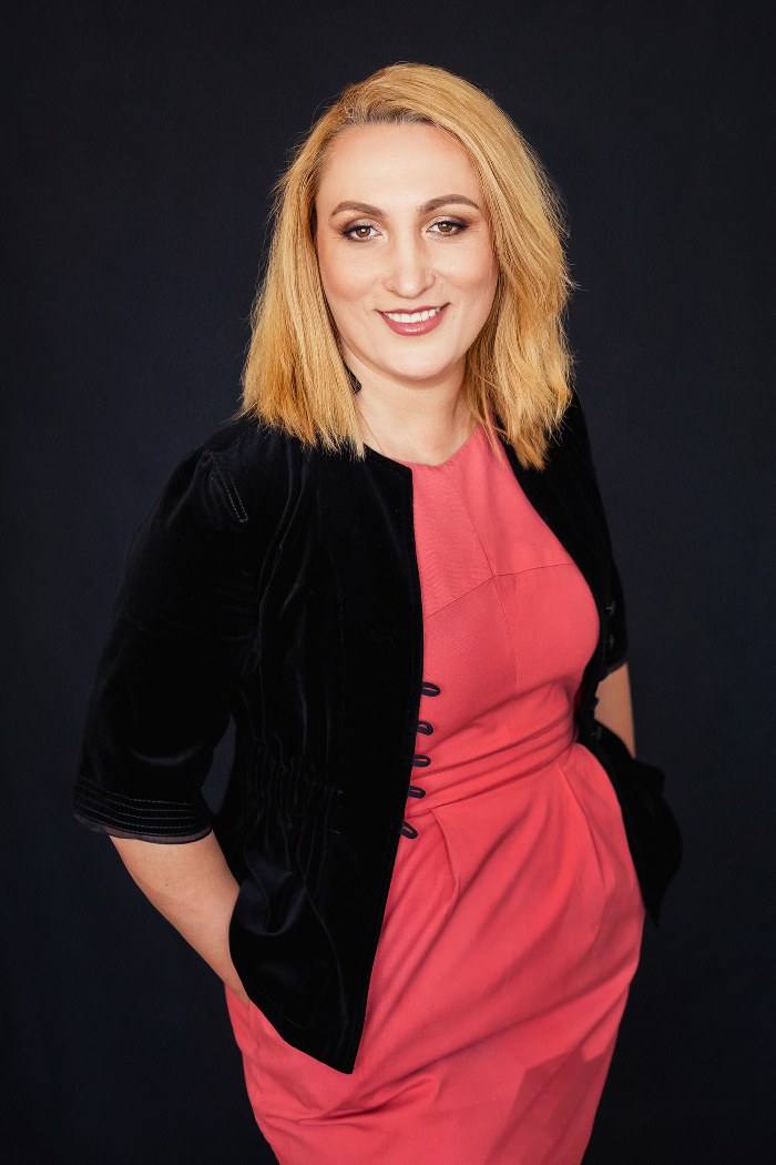 Portret editorial Mirela Pascu, rochie corai, jachetă neagră, fundal sobru